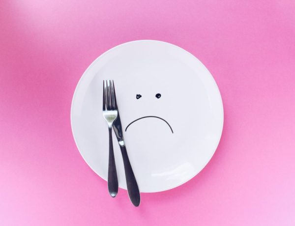 a white round plate with a frowny face drawn onto it in black
