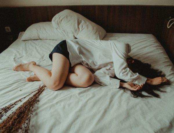 Woman lying across bed sad