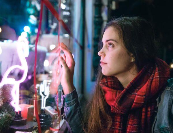 woman staring into Christmas shop window at night